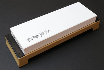 White whetstone on wooden base with black abrasive strip at one end