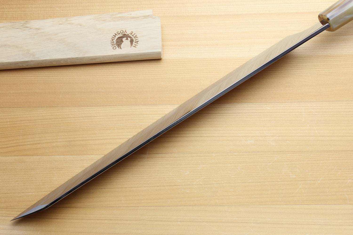 Long knife with wooden sheath on a wooden surface