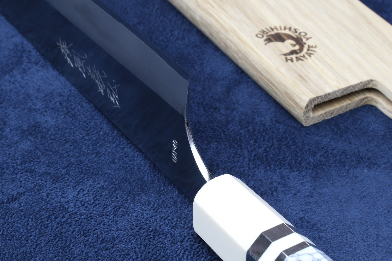 Knife heel shown on blue background with saya cover next to it