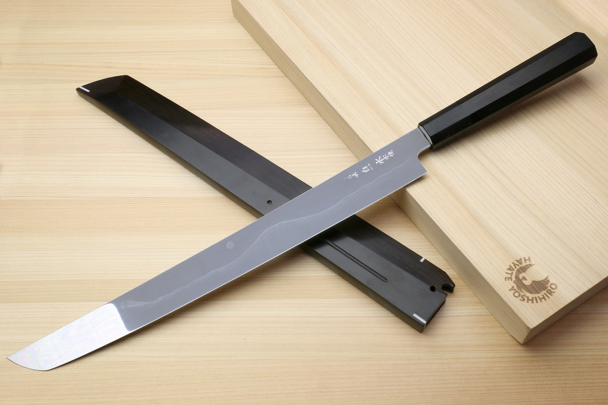 Japanese kitchen knife with silver blade, black handle, and dark sheath shown together