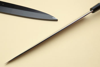 Japanese chef knives with pointed silver blades and black striped handles, angled view