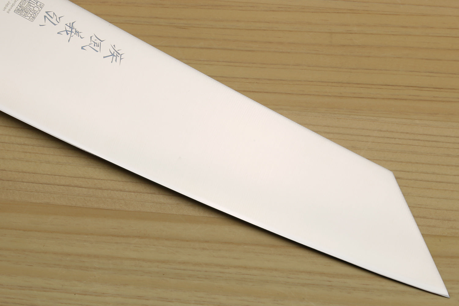Kiritsuke chef knife tip and edge with etched markings; white blade and ivory-look bolster.