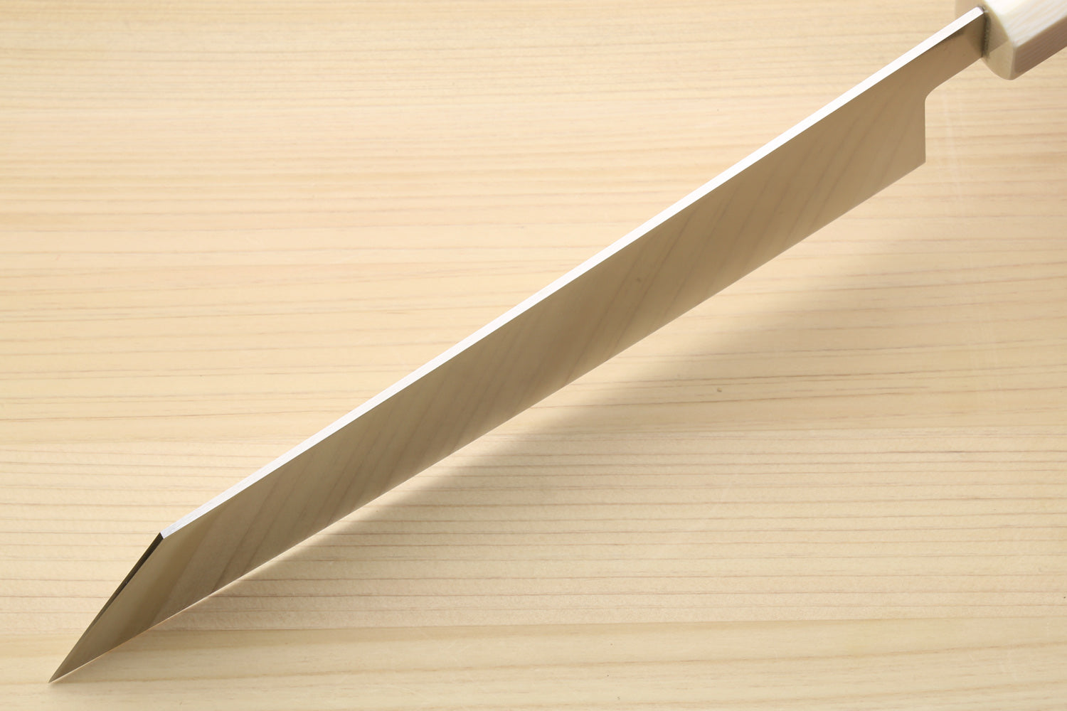 Kiritsuke chef knife blade side, showing spine curve and white bolster on rosewood handle.