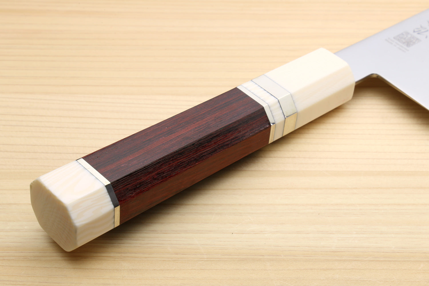 Rosewood handle end with white bolster; white Kiritsuke chef knife blade in view.