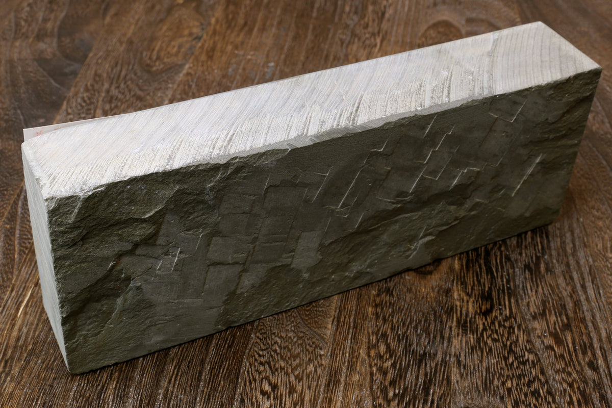 Natural whetstone finishing stone, dark grey rectangular block with striated texture