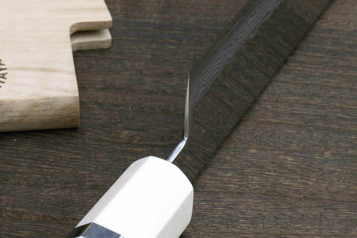 White howlite santoku handle with ivory-toned bolster and damascus blade edge close-up