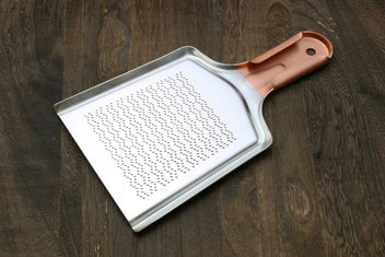 Radish grater with copper-toned handle and perforated grating face
