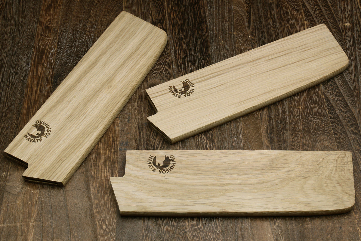 Multiple oak wood saya blade covers with embossed logos, shown laid out
