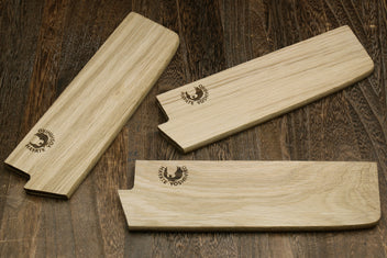Multiple oak wood saya blade covers with embossed logos, shown laid out