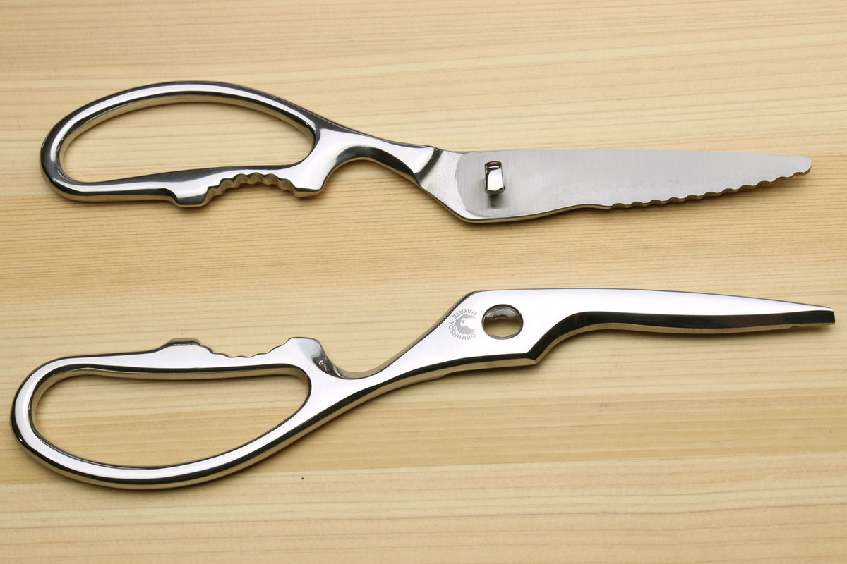 Stainless steel shears with serrated blades and oval loop handles, side view.