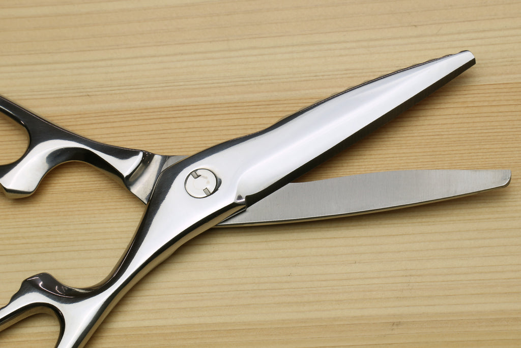 Stainless steel shears with serrated blades, riveted pivot, and loop handles.