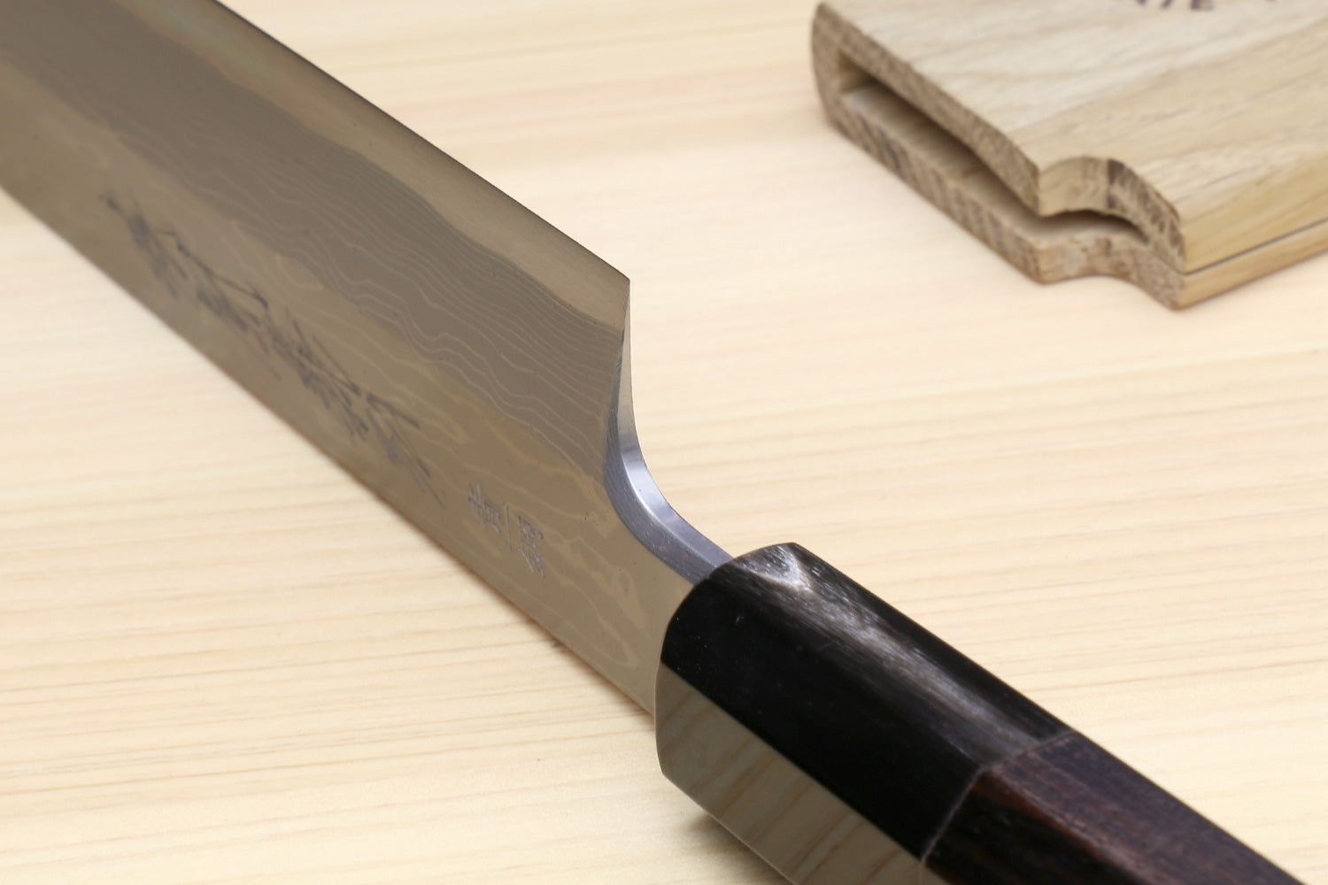 Damascus yanagi knife heel on a wooden cutting board