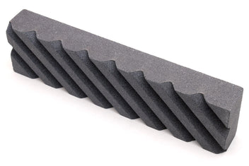 Black sharpening stone with grooved, ridged pattern along a long face