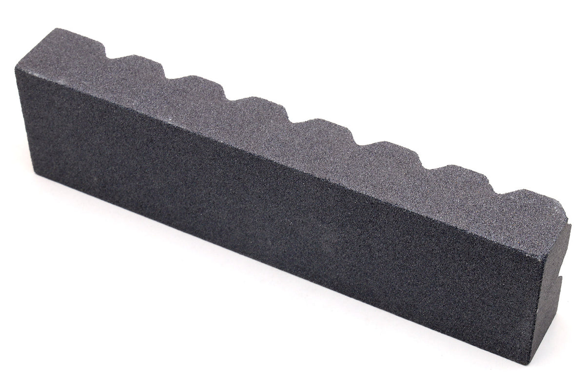Black sharpening stone with scalloped notches along the top edge
