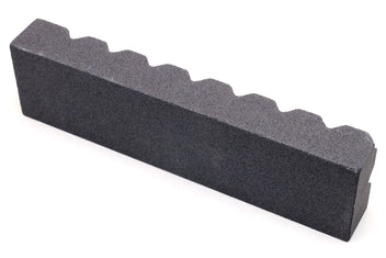 Black sharpening stone with scalloped notches along the top edge