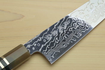 Chef gyuto knife close-up: dark Damascus blade with curved handle and scalloped edge