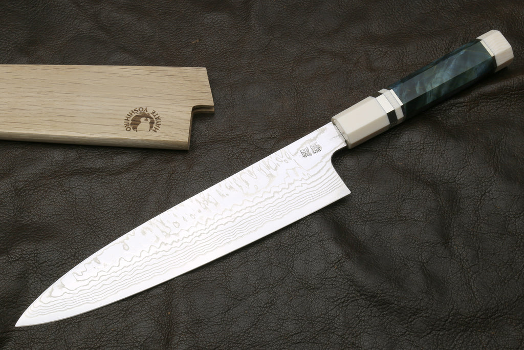 Chef's damascus knife on a dark surface, accompanied by a wooden sheath