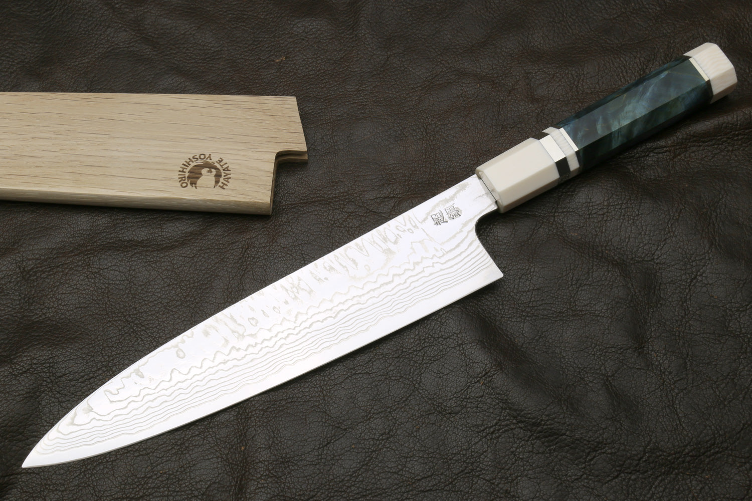 Chef's damascus knife on a dark surface, accompanied by a wooden sheath