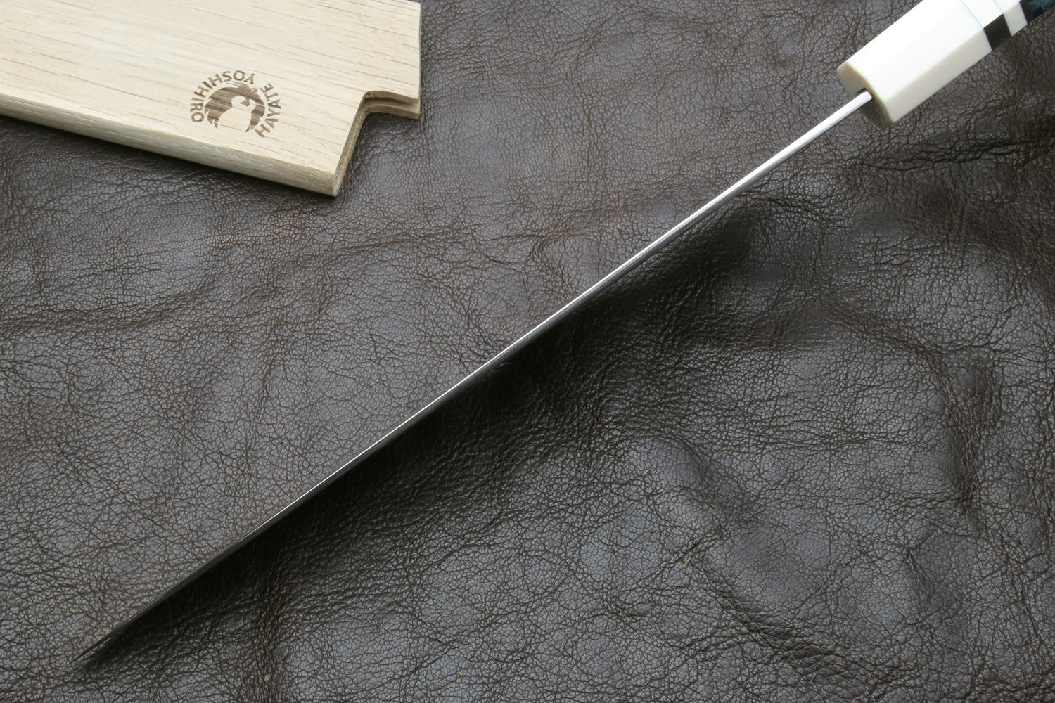 Spine of a knife blade on a dark surface, accompanied by a wooden sheath