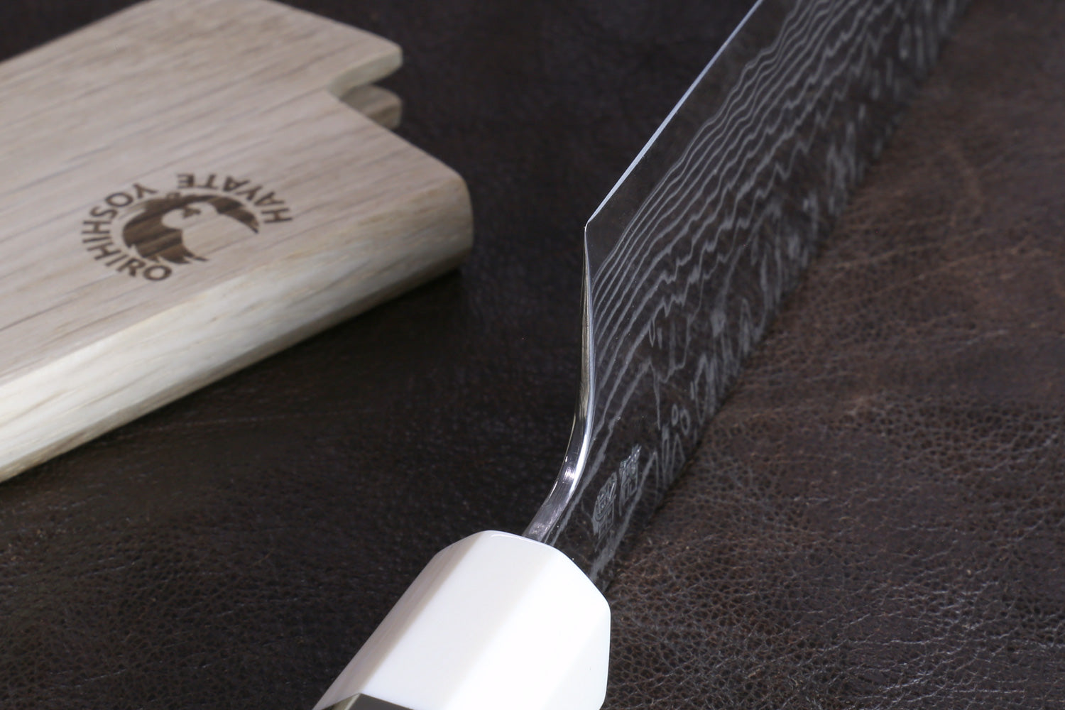 Knife heel with a wooden handle on a dark surface, accompanied by a wooden sheath