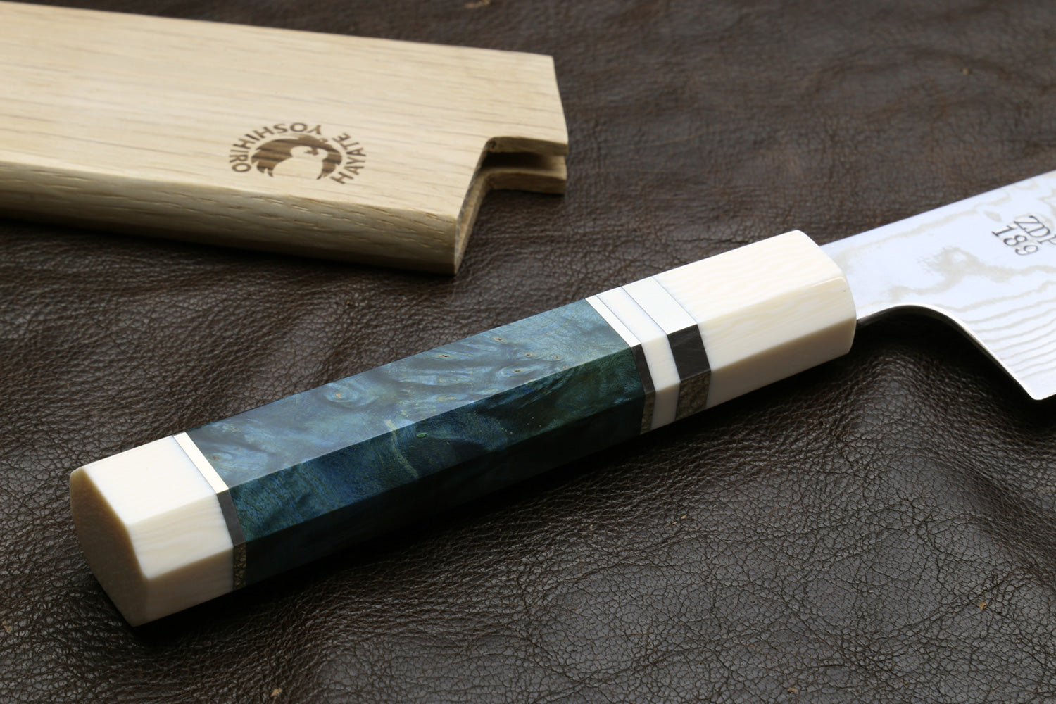  Decorative handle on a dark surface, accompanied by a wooden sheath.
