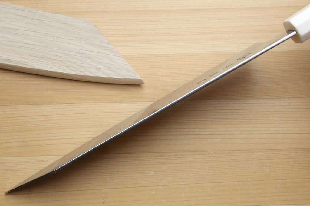 Spine of the blade, accompanied by a wooden sheath on a light wooden surface