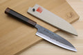 Petty utility knife with ebony handle and blue-gray kurouchi blade on wooden boards
