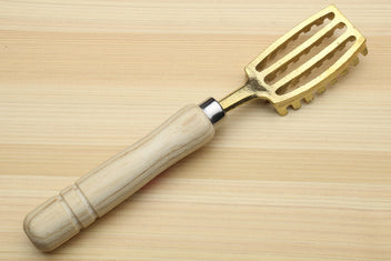 Fish scaler tool with light wood handle and gold metal head with raised ridges