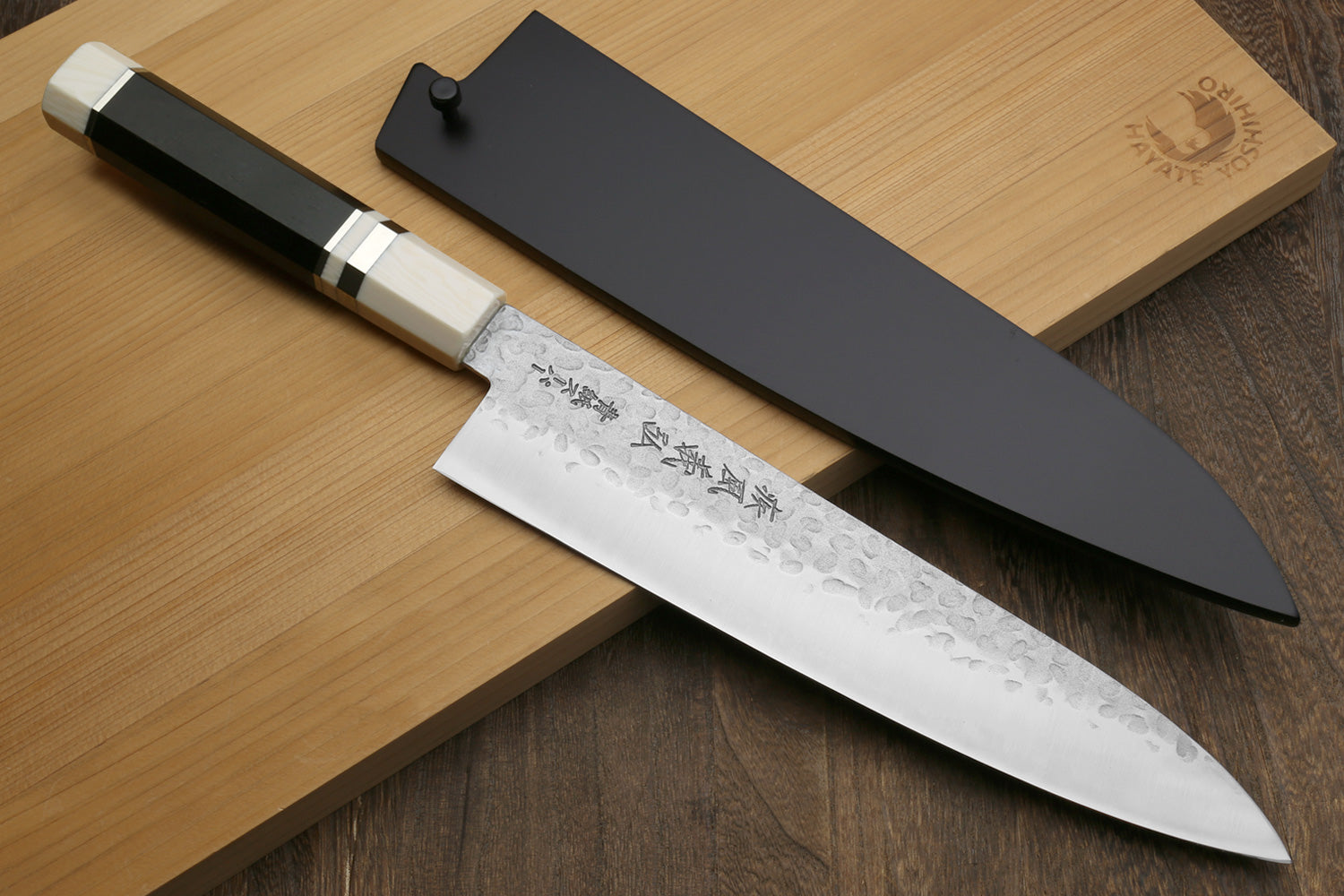Chef's knife with a black sheath on a wooden surface