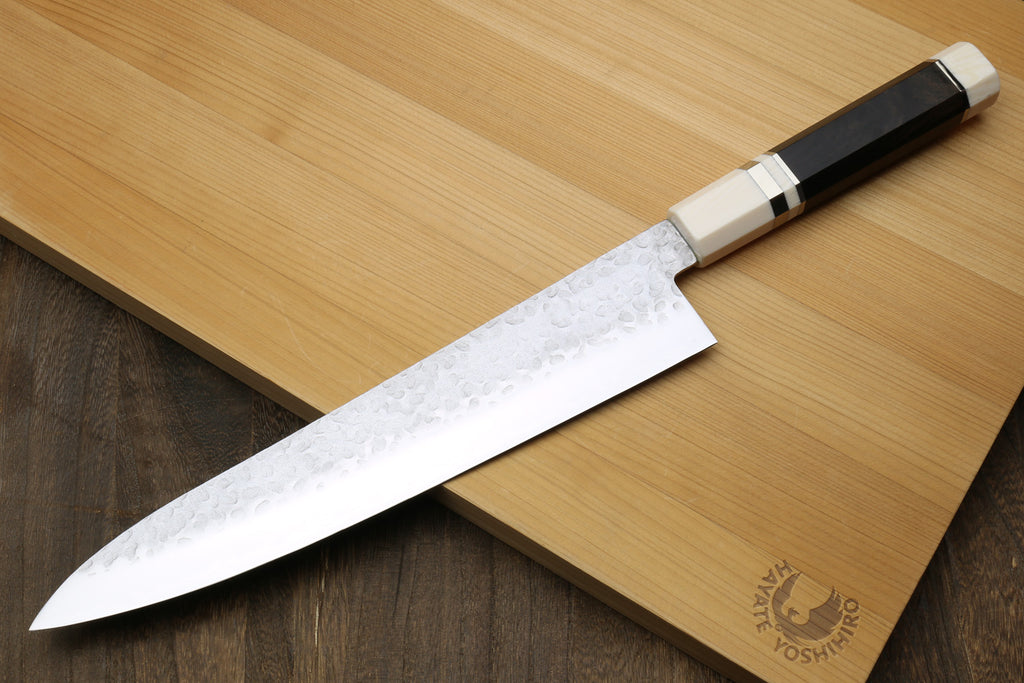 Back side of a Chef's knife with ebony wood handle on a wooden cutting board