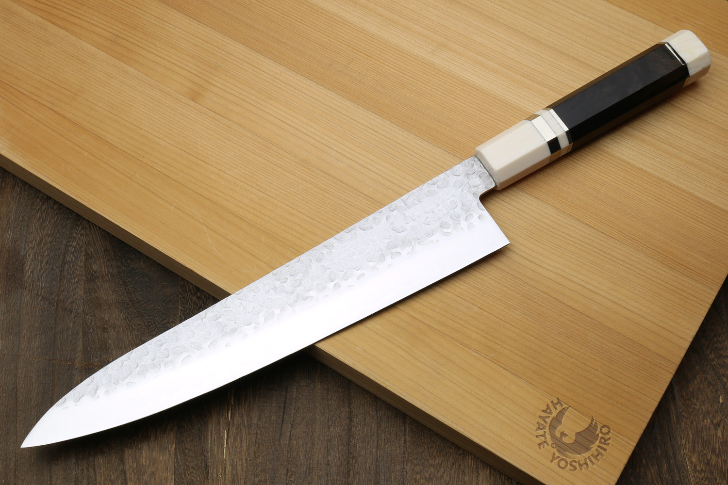 Back side of a Chef's knife with ebony wood handle on a wooden cutting board