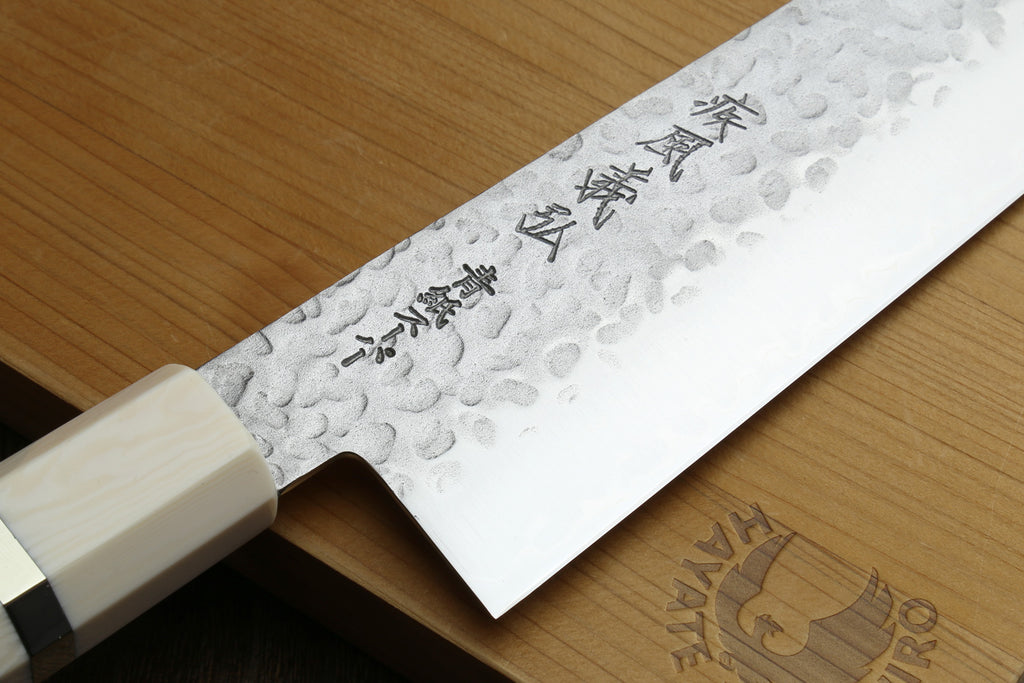 Textured blade of Super Blue Steel  featuring engraved text on a wooden surface