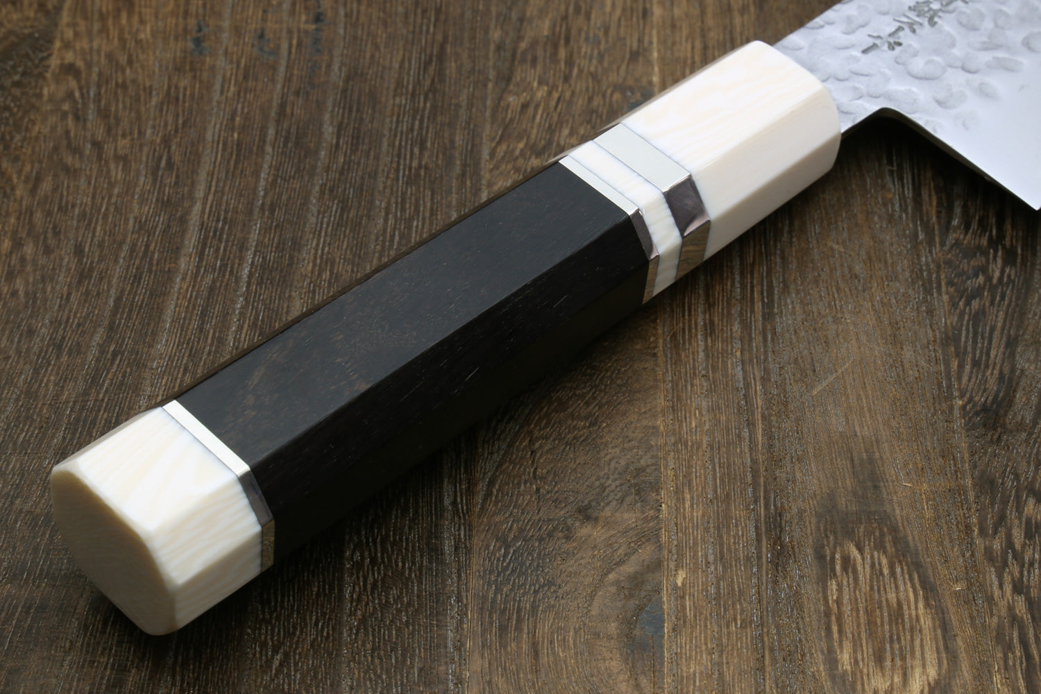 Close-up of a handle of the knife with a black and white handle on a wooden surface