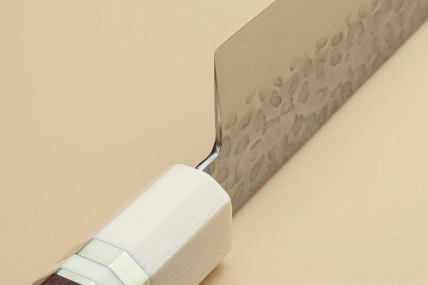 Chef's gyuto knife heel close-up: hammered blade, ivory bolster, rosewood handle