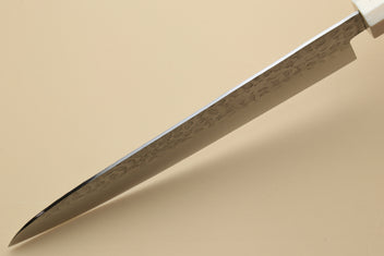 Chef's gyuto knife tip close-up with hammered stainless steel blade and ivory bolster
