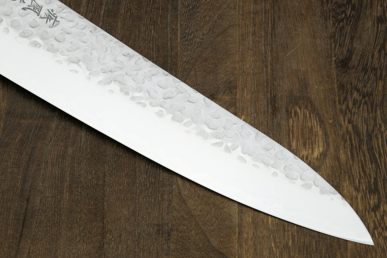 Chef's gyuto knife side view of hammered stainless blade with pointed tip
