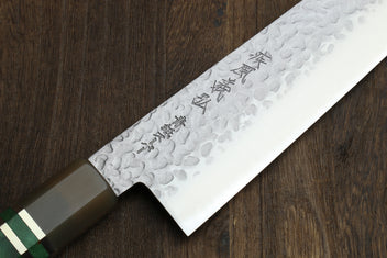 Gyuto chef knife blade close-up with hammered pattern and engraved markings