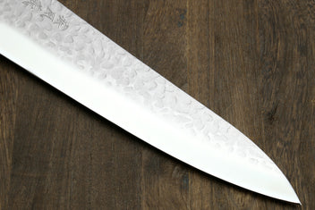 Gyuto chef knife blade edge close-up with hammered texture and pointed tip
