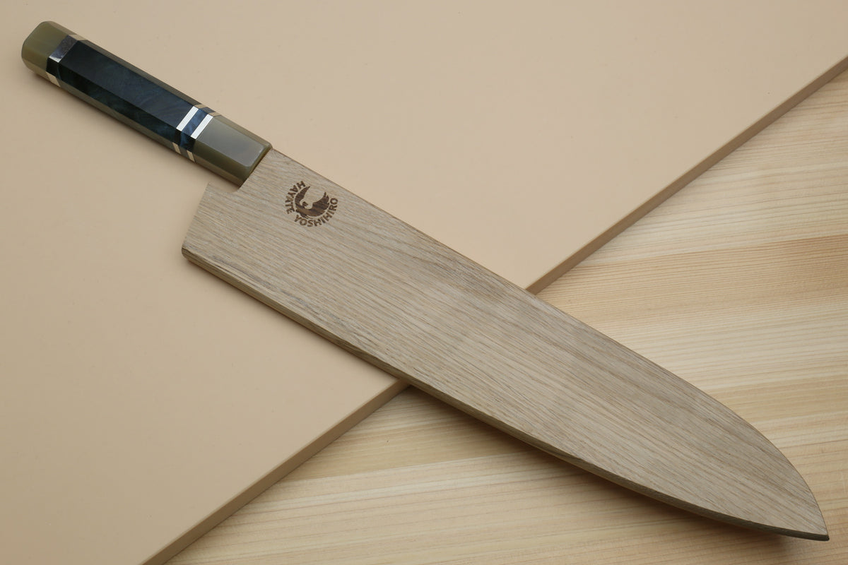 Gyuto chef's knife partly covered by a wooden blade guard