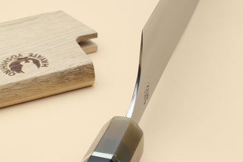 Yoshihiro Hayate knife close-up of blade spine and handle junction beside wooden sheath
