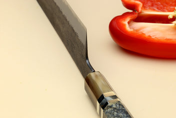 Nakiri vegetable knife blade close-up with dark forged finish and stamped markings