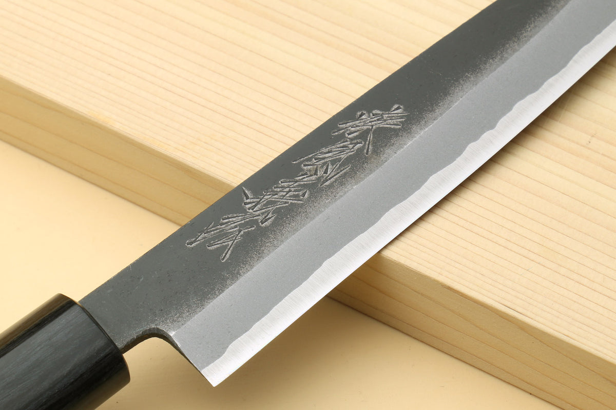 Petty knife close-up of blue steel blade with engraved markings and dark handle