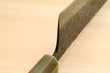 Nakiri blade edge view with dark damascus pattern and ironwood handle