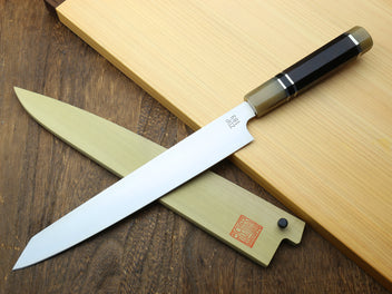 Sujihiki kiritsuke knife with white blade, dark horn handle, and wooden sheath.