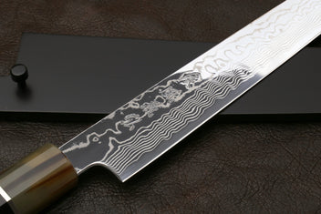 Sujihiki slicer knife with close-up damascus pattern on blade and dark handle rings