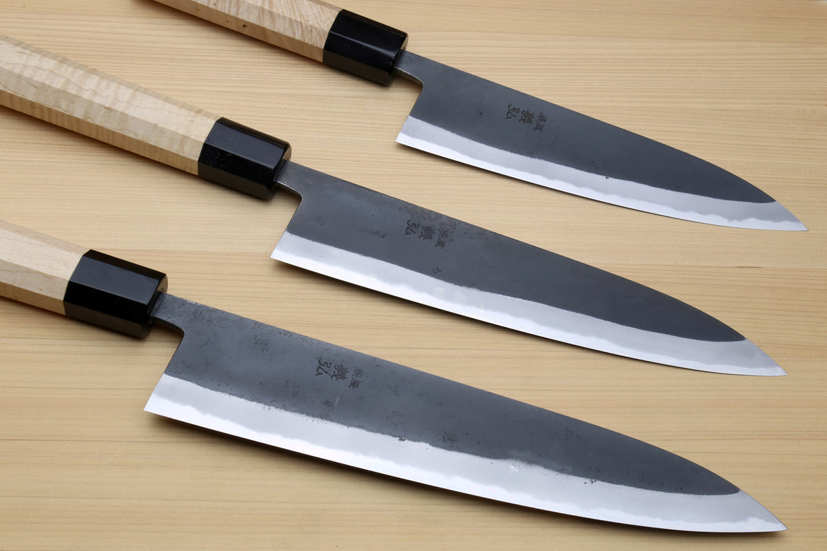 Set of blue steel kurouchi gyuto knives with light Kaede handles and black collars