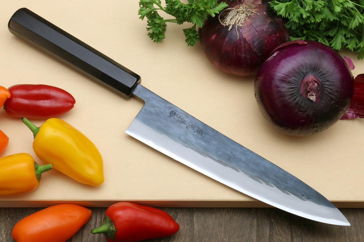 Two kitchen knives with black handles and silver stainless blades on a cutting board.
