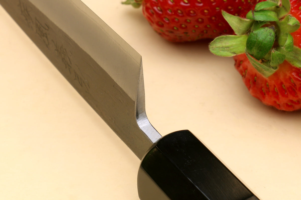Petty utility knife with stainless blade and dark ebony handle, bolster and curve close-up
