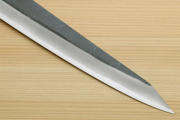 Sujihiki slicer knife with long silver blade and narrow pointed tip; dark handle partial.