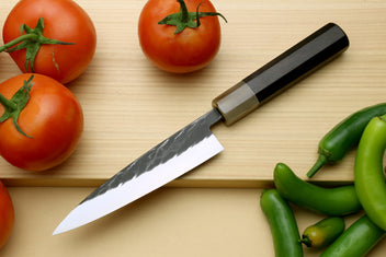 Petty utility knife with black-and-silver handle and gray blade, tip down